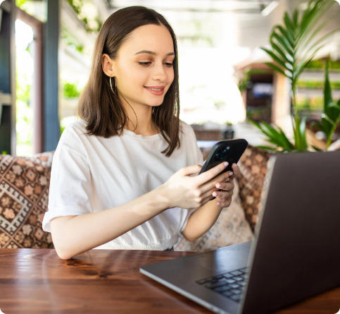freelance-young-woman-sitting-in-the-cafeteria-with-laptop-and-drinking-coffee-while-use-her-phone
